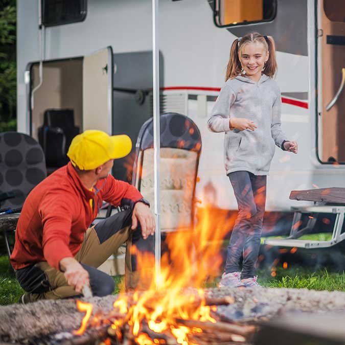 Father and daughter prepare campfire beside RV at the Castle Rock Lake Campground in Necedah Wisconsin